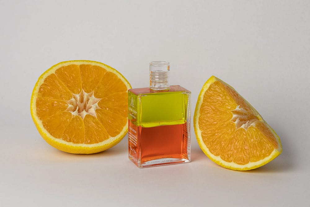 Produktfoto einer AURA-SOMA Equilibrium Flasche Gelb-Orange mit einer aufgeschnittenen Orange